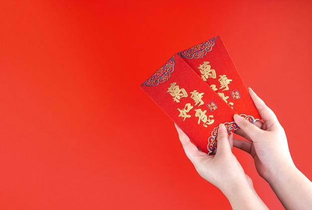 Ręka kobiety trzymająca czerwoną kopertę lub czerwoną paczkę prezent pieniężny lub Ang pao z chińskim zdaniem oznacza wszystko lub wszystko ma znaczenie Koncepcja chińskiego nowego roku Odosobniona czerwień