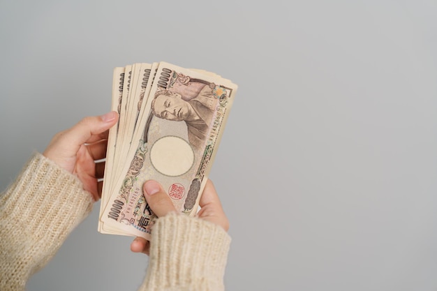 Ręka kobiety trzymająca stos banknotów jena japońskiego Tysiąc jenów pieniądze Japonia gotówka Recesja podatkowa Gospodarka Inflacja Finansowanie inwestycji i zakupy koncepcje płatności