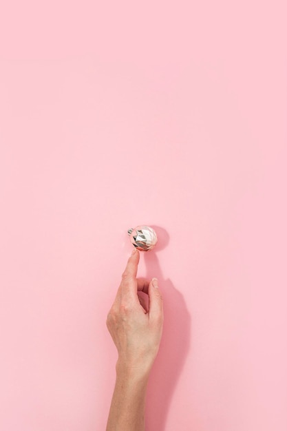 Ręka kobiety wskazuje na jedną ozdobną kulę na różowym tle Widok z góry leżał płasko