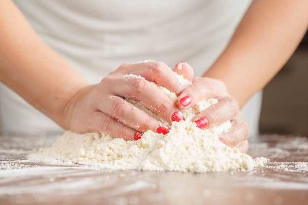 Ręka Kobiety Wyrabia Ciasto Na Ciasto Drożdżowe Na Drewnianym Stole, Przygotowując Ciasto Drożdżowe