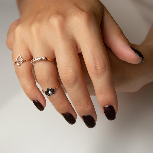 Ręka kobiety z czarnym lakierem do paznokci i pierścionkiem z brylantem.