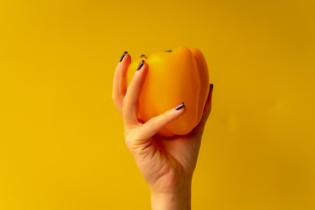 Ręka kobiety z warzywami na żółtym tle zdrowe życie żółty ogórek