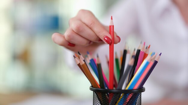 Ręka kobiety z wyciąga czerwony ołówek w biurze zbliżenie