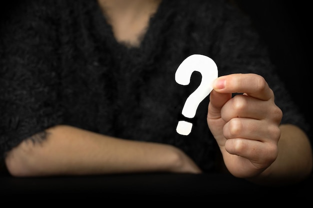 Ręka kobiety znakiem zapytania. Ikona pytania, symbol na czarnym tle. Koncepcja wątpliwości, edukacja lub zdjęcie FAQ