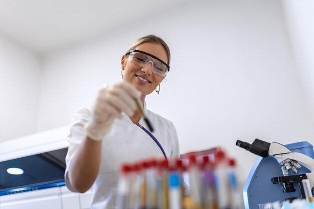 Zdjęcie ręka lekarza pobierająca probówkę z próbką krwi ze stojaka z maszynami do analizy w tle laboratoryjnym technik trzymający test probówki z krwią w laboratorium badawczym