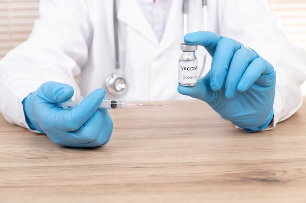 Ręka lekarza trzymając fiolkę szczepionki na biurku lekarza