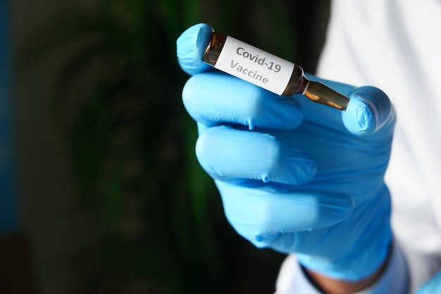 Ręka lekarza w rękawiczkach ochronnych, trzymając szczepionkę koronawirusa z miejsca na kopię