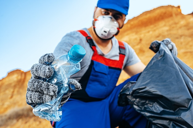 Zdjęcie ręka mężczyzny ochotnika chwytającego plastikowe śmieci do worka na śmieci sprzątającego plażę