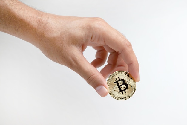 Ręka mężczyzny trzyma złoty bitcoin na białym tle