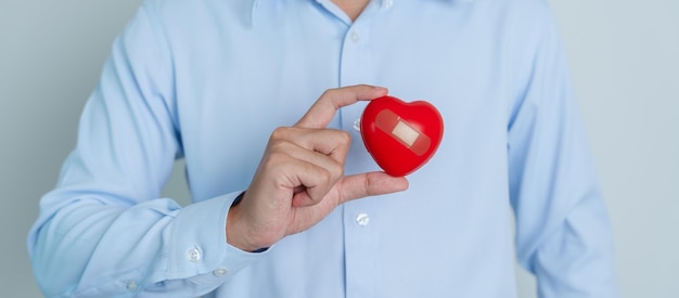 Ręka mężczyzny trzymającego czerwone serce kształt miłości dawcy światowy dzień serca światowy dzień zdrowia i koncepcje ubezpieczeniowe