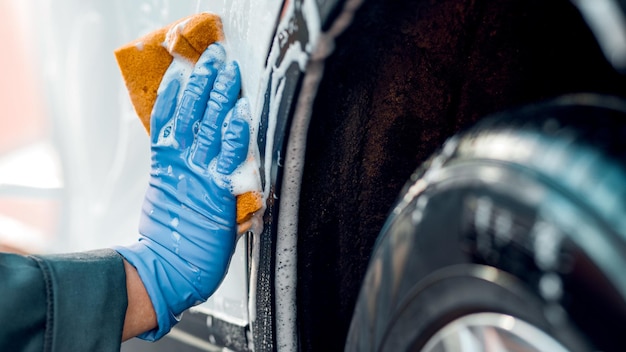 Ręka mężczyzny w rękawiczkach mężczyzna myje koło samochodu