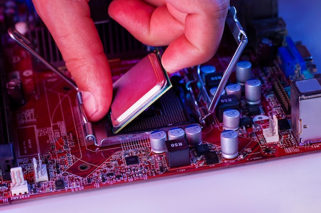 Ręka mężczyzny wkłada procesor do chipsetu płyty głównej