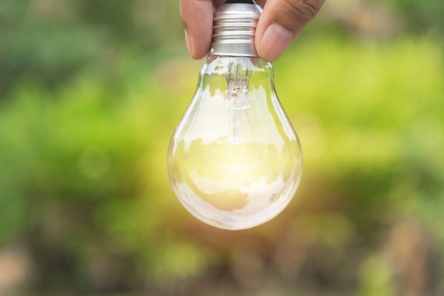 Ręka osoby mienia żarówka dla pomysłu, sukcesu lub energii słonecznej