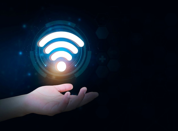 Ręka osoby trzyma symbol wifi izolowany na ciemnym tle dostępu do sieci.