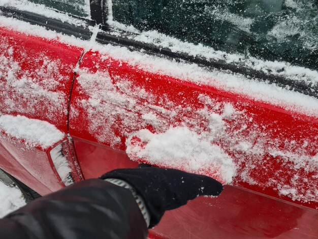 Ręka otwiera pokrytą śniegiem klamkę drzwi samochodu z zewnątrz