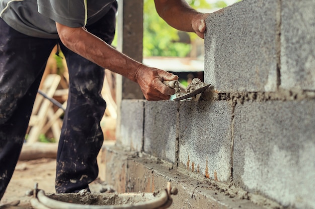 Ręka pracownika gipsowania cement na ściana z cegieł przy budową