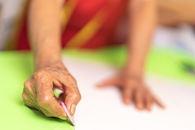 Ręka pracownika używającego markera na stole do krojenia w warsztacie włókienniczym