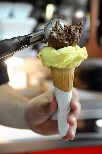 Ręka przygotowuje lody z brązowej i żółtej czekolady