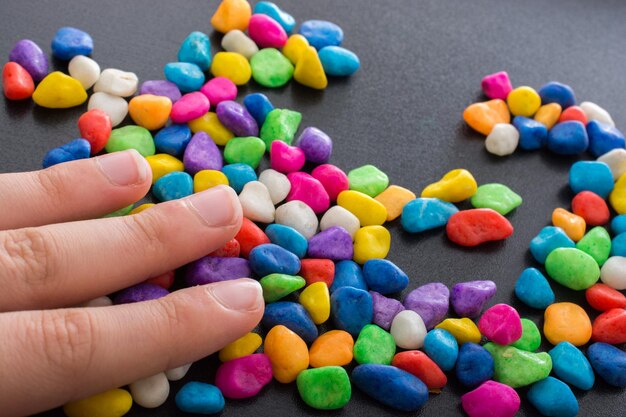 Zdjęcie ręka sięga po stos kolorowych cukierków.