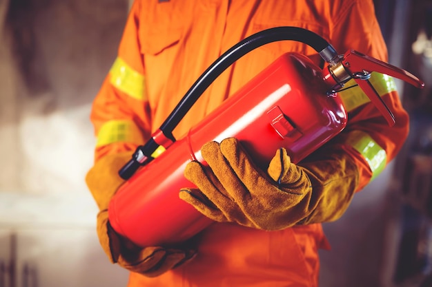 Ręka strażaka trzymająca gaśnicę dostępna w sytuacjach awaryjnych w tle uszkodzenia pożaru Koncepcja bezpieczeństwa