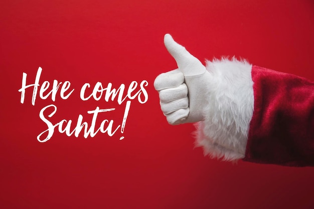 Ręka Świętego Mikołaja kciuk w górę ze świąteczną wiadomością