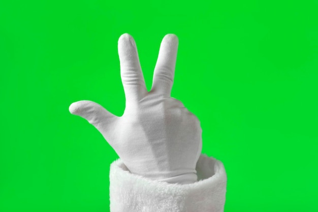 Ręka Świętego Mikołaja pokazująca trzy palce na tle klucza chrominancji Ręka w białych rękawiczkach Gestykulująca liczba izolowana na zielonym ekranie Obliczanie dłoni z palcami Punkt początkowy liczenia numer 3