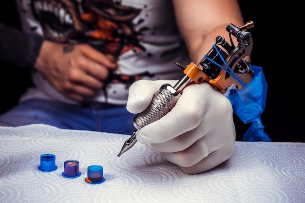 Ręka tatuażysty trzymająca pistolet do tatuażu