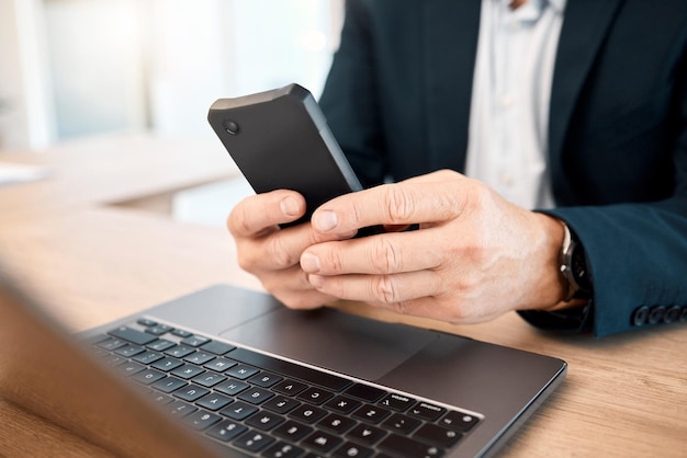 Ręka telefon i badania z biznesmenem wpisując wiadomość tekstową podczas pracy na swoim laptopie Komunikacja mobilna i sieć z męskim kierownikiem lub pracownikiem czytającym e-mail w pracy
