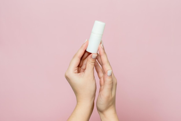 Ręka trzyma białą butelkę Krople do nosa lub ucha w dłoni na różowym tle Produkt farmaceutyczny
