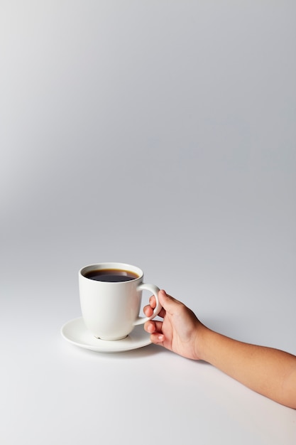 Zdjęcie ręka trzyma białą filiżankę kawy