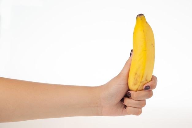 Ręka trzyma całego banana na białym tle