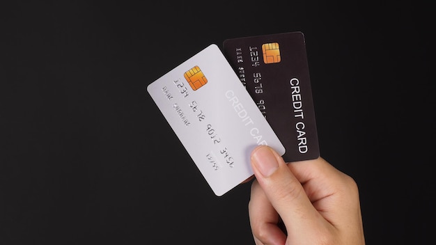 Ręka trzyma dwie karty kredytowe Karty kredytowe koloru czarnego i srebrnego samodzielnie na czarnym tle