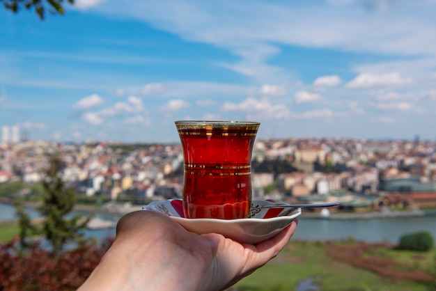 Ręka trzyma filiżankę tradycyjnej tureckiej herbaty na tle Stambułu, Turcja