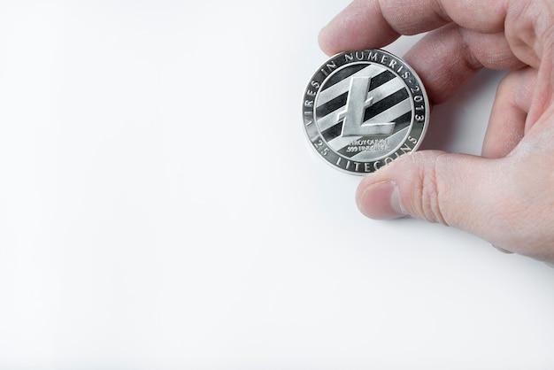 Zdjęcie ręka trzyma jeden litecoin na białym tle