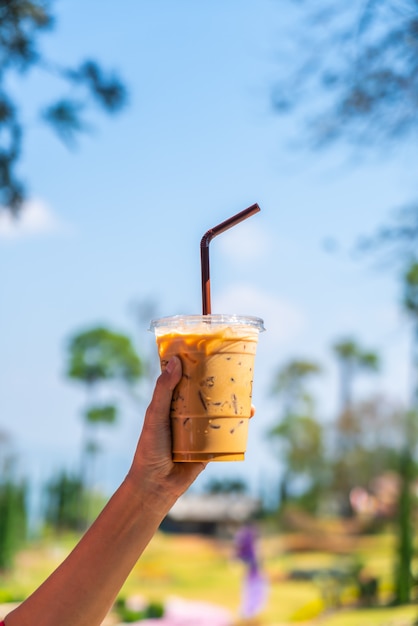 ręka trzyma kubek mrożonej kawy latte