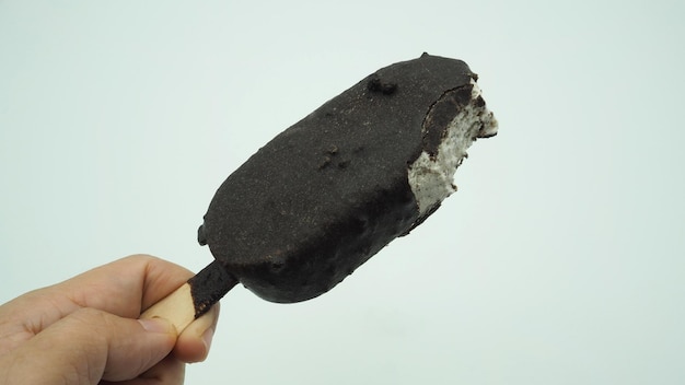 Zdjęcie ręka trzyma lody z kawałkami ciasteczek pokrytymi polewą czekoladową