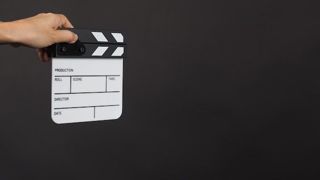 Ręka trzyma małą białą tablicę clap lub plansz filmowy. Znajduje zastosowanie w produkcji wideo, filmach, filmach, przemyśle kinowym na czarnym tle.