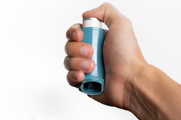 Ręka trzyma niebieski inhalator astmy.