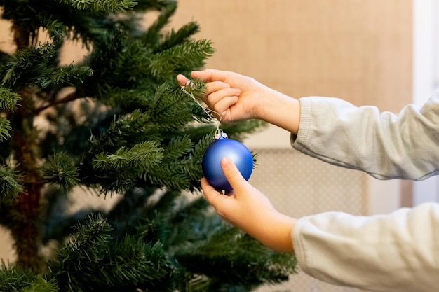 Ręka trzyma niebieski ornament kulkowy z bliska dekorowanie choinki w domu zimowe wakacje