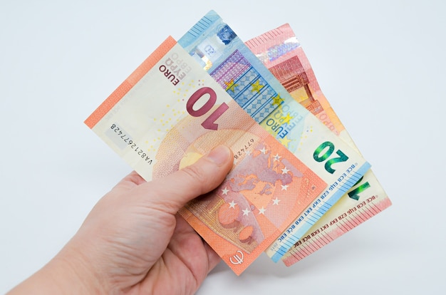 Ręka trzyma papierowe banknoty euro o nominałach 10 i 20