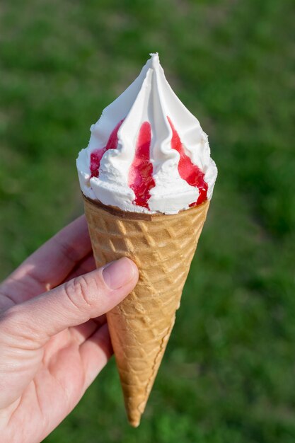 Ręka trzyma piękne lody na zielonym tle.