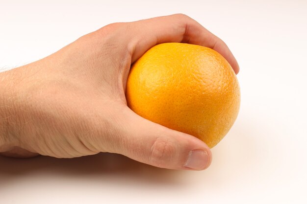 Ręka trzyma pomarańczę na białym