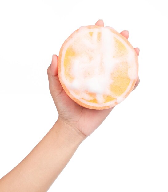 ręka trzyma Pomarańczowa gąbka mokra z pianką odizolowywającą na białym tle.