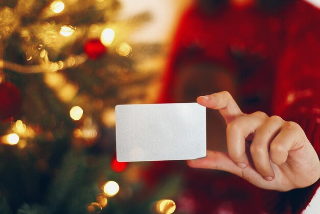 Ręka trzyma pustą kartę kredytową w pięknej choince świeci świąteczna wyprzedaż i makieta koncepcji zakupów wesołych świąt i szczęśliwego nowego roku koncepcja miejsca na tekst sezonowa sprzedażxA
