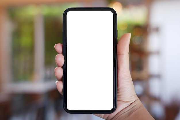 Zdjęcie ręka trzyma smartphone z pustego ekranu dla aplikacji na wnętrze kawiarni