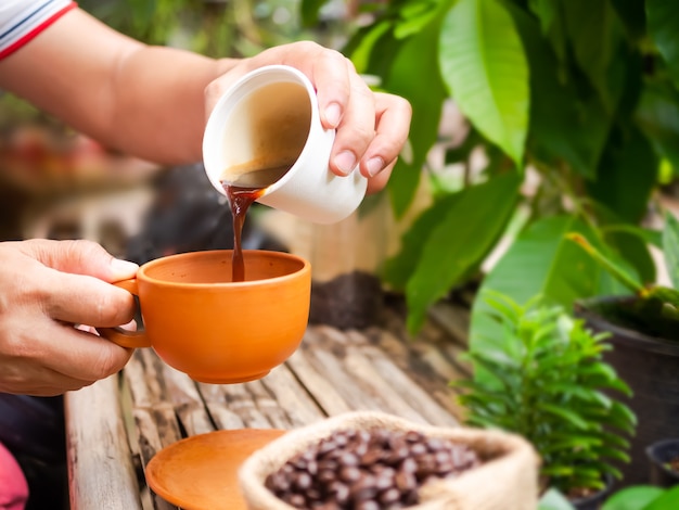 Ręka trzyma szklankę do wlewania kawy espresso do filiżanki kawiarnia napój spożywczy Uprawa ekologicznej koncepcji kawy