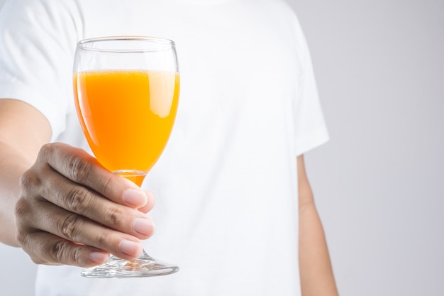 Ręka trzyma szklankę soku pomarańczowego