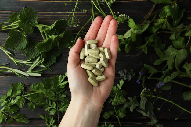 Zdjęcie ręka trzyma tabletki ziołowe, widok z góry