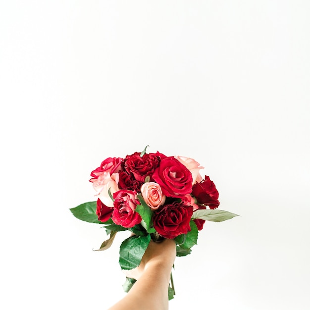 Ręka trzymać różowy i czerwony bukiet kwiatów róży na białym tle