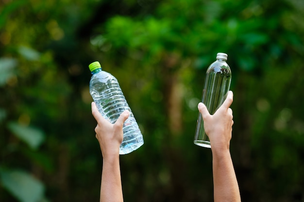 Ręka Trzymaj pustą szklankę wody i plastikową butelkę